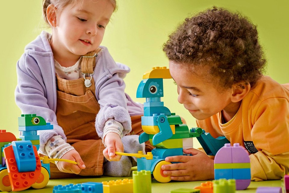 Two children playing with a LEGO DUPLO 3in1 Dinosaurs on Wheels, Learning toy set.